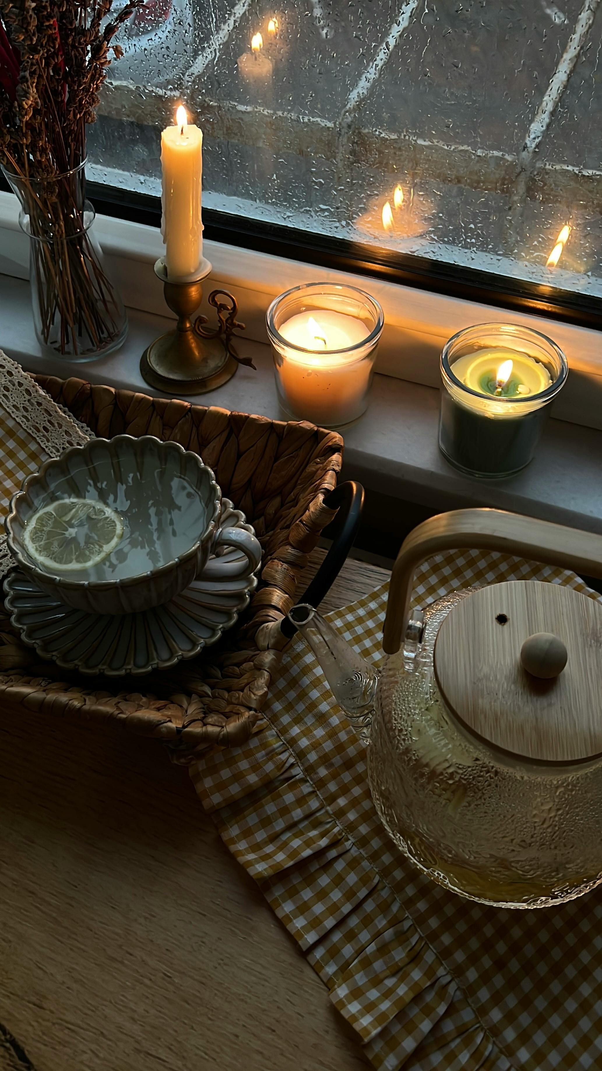 Candles and tea by a rain-streaked window